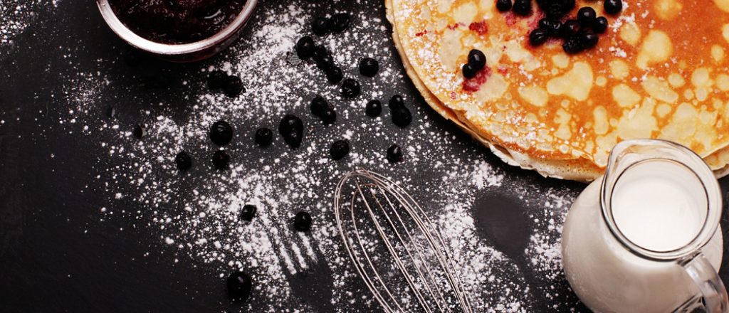 Boekweitpannenkoek met blauwe bessen op een besmeurd bord.