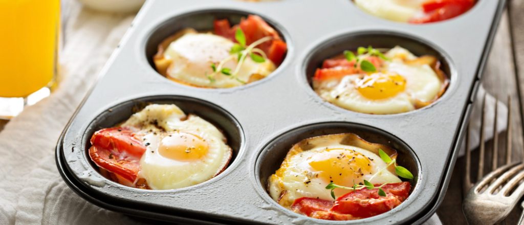 Gebakken eieren met tomaten in een muffinvorm.