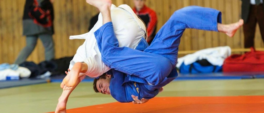 Judo-atleet in blauwe gi voert worp uit