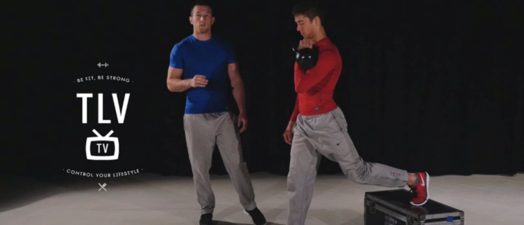 Twee mannen doen een kettlebell oefening binnen.