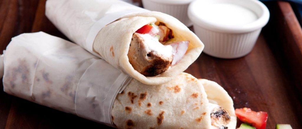 Twee kip gyros wraps met tzatziki op houten bord