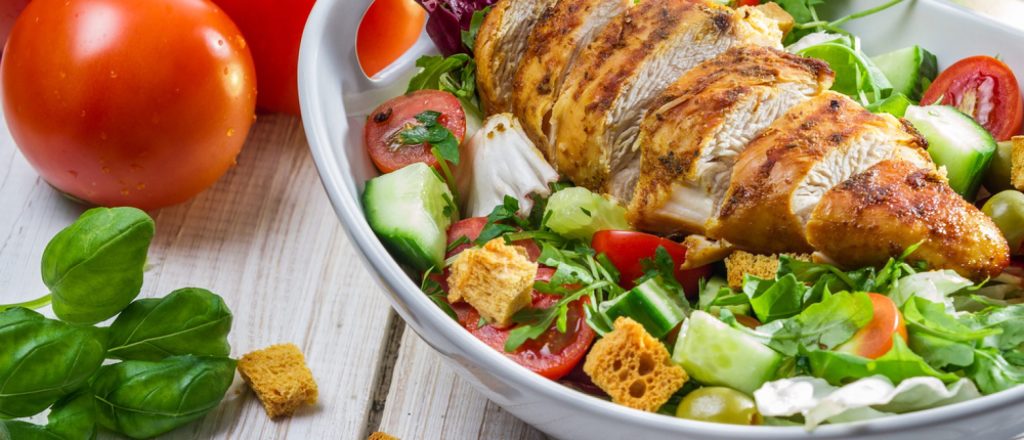 Gesneden kip ketjap op een frisse salade met komkommer.