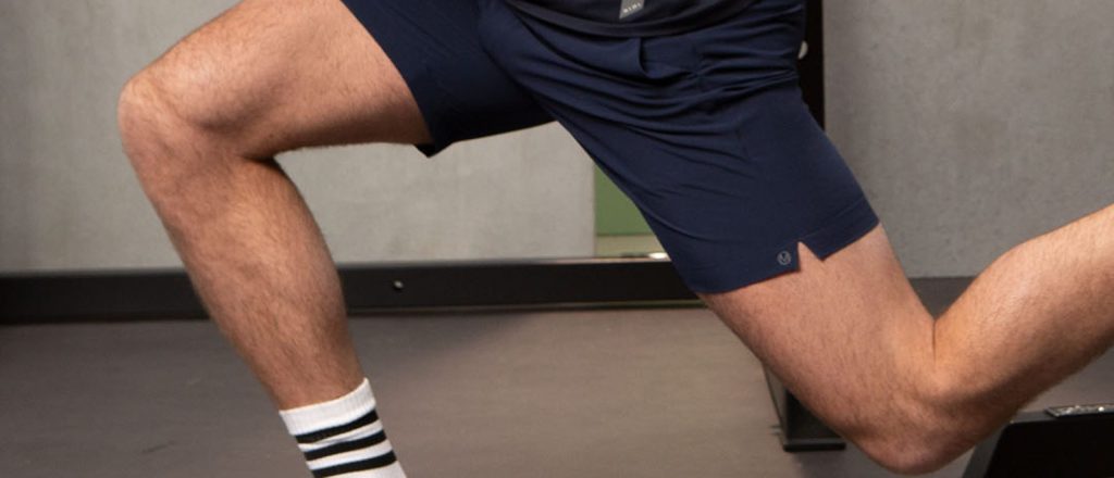 Man in sportkleding doet lunge oefening binnen