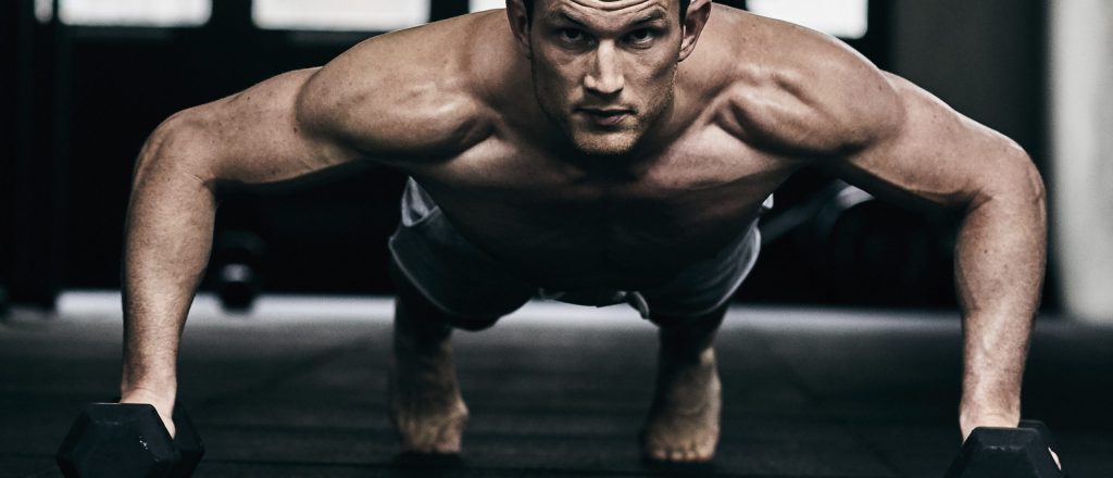 Man doet push-ups met dumbbells in de sportschool