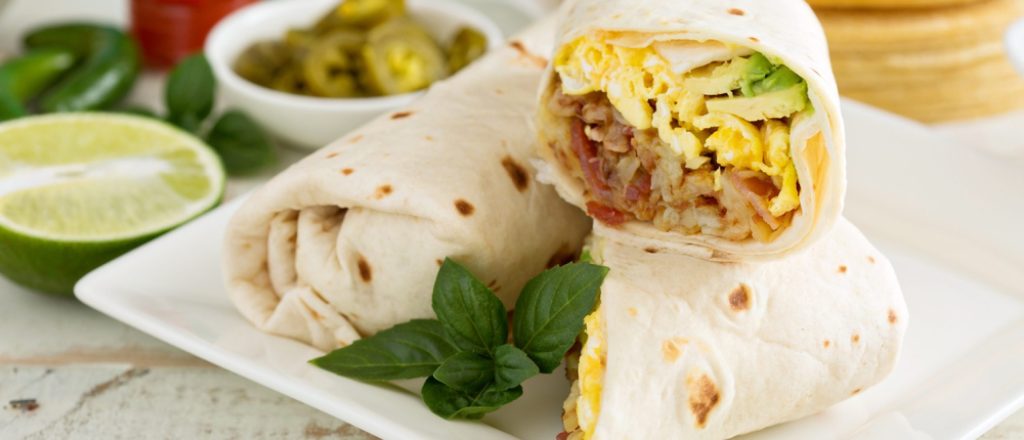 Geserveerde wrap met ei, bacon en avocado op een bord.
