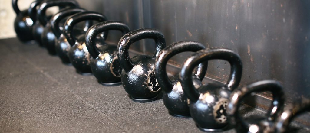Een rij zwarte kettlebells in een sportschool.