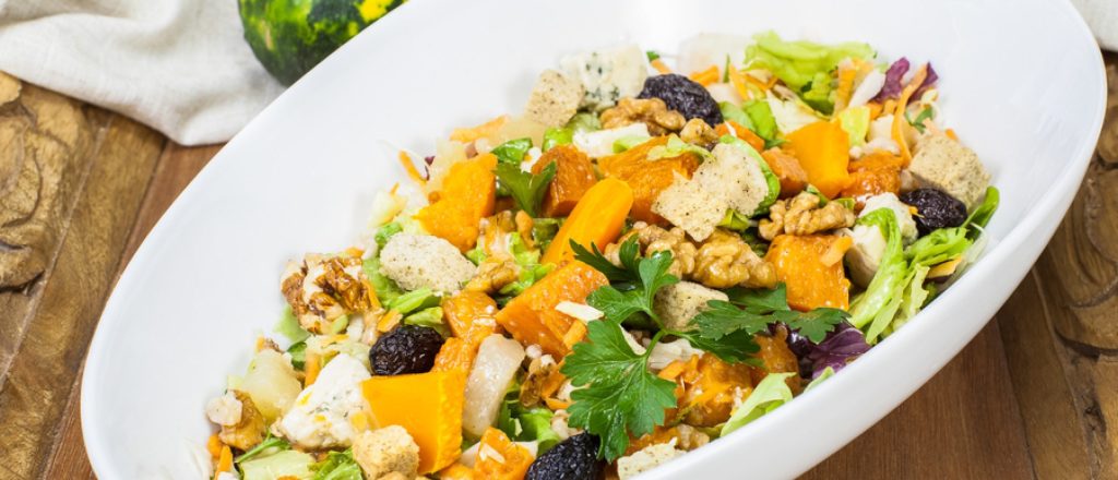 Kleurrijke salade met pompoen en geitenkaas in kom.
