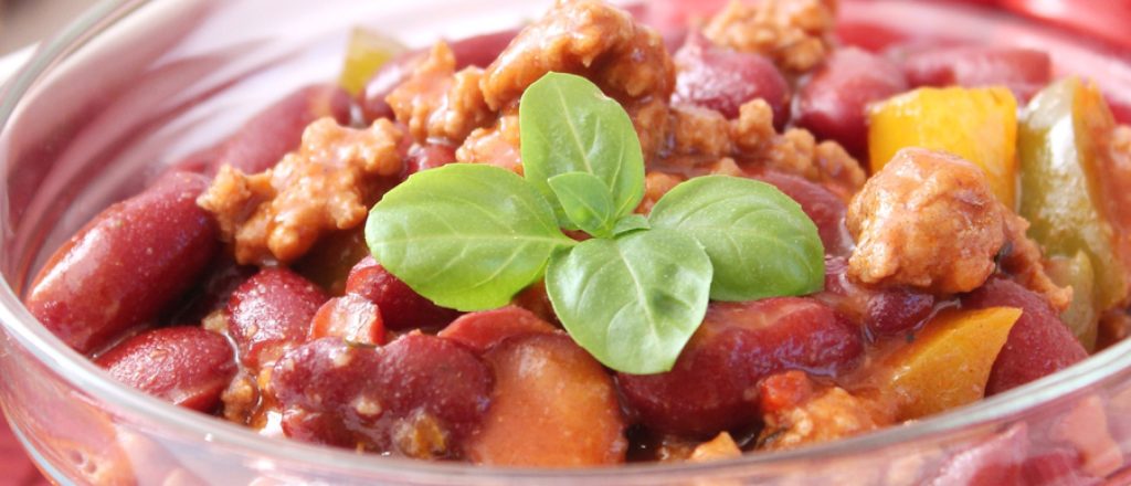 Bord met stoofvlees, kidneybonen en basilicum.