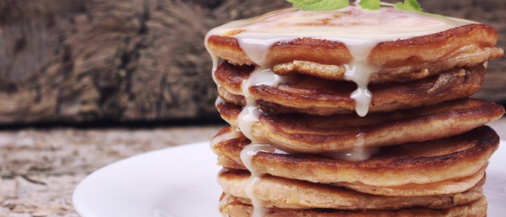Stapel vanillepannenkoeken met yoghurt erop gegoten.