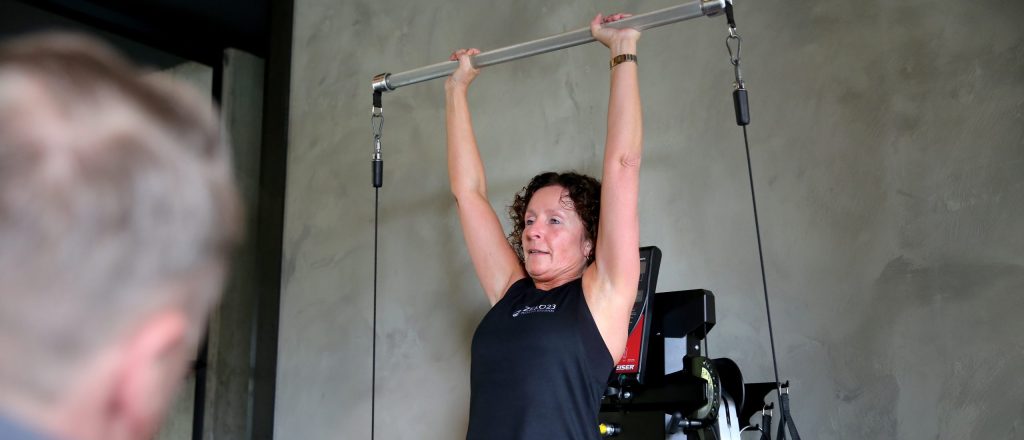 Vrouw heft gewichten tijdens training bij Zero23.