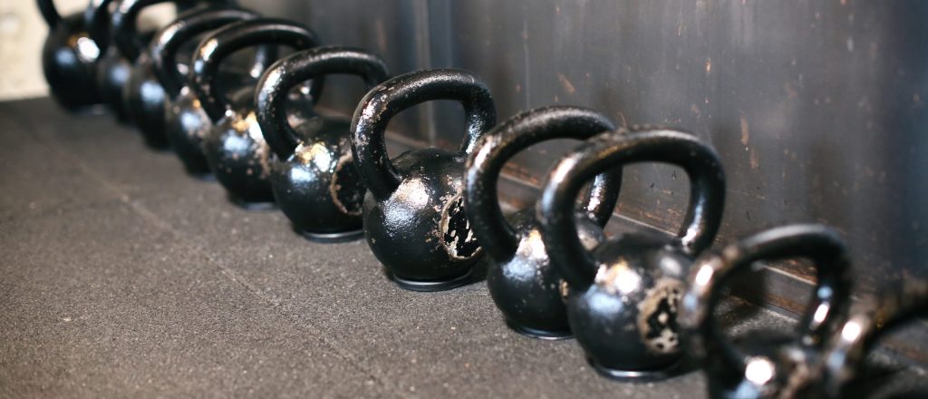 Rij zwarte kettlebells in een fitnesszaal.
