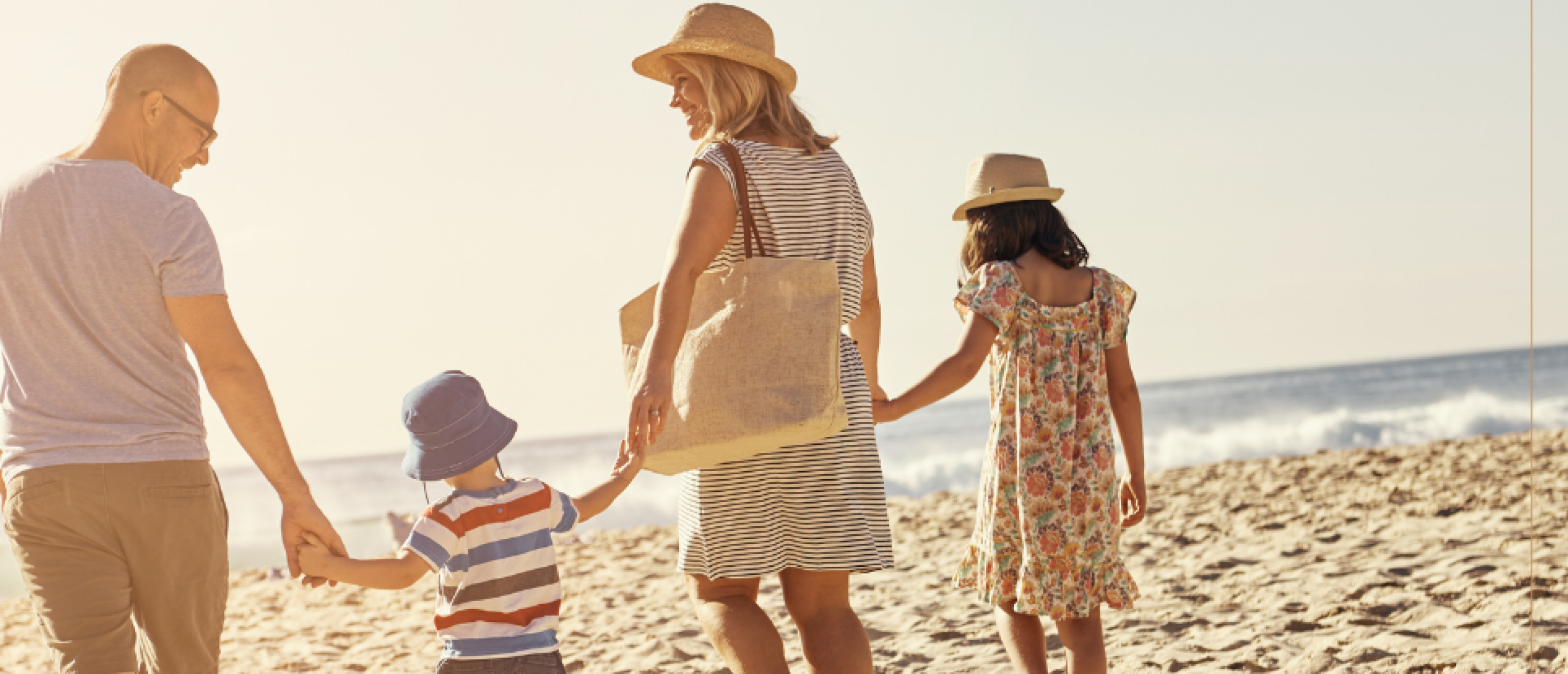Een gezin wandelt hand in hand op het strand.