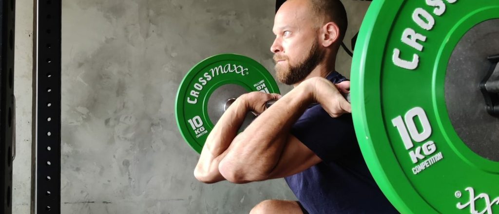 Man doet gewichtheffen met groene halterschijven