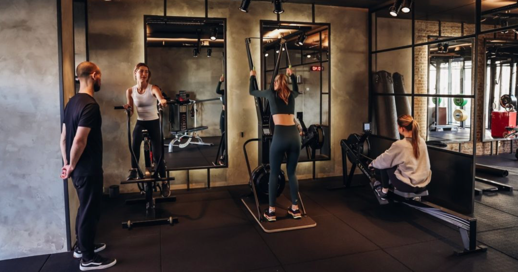 Drie vrouwen en een man sporten in een moderne studio.