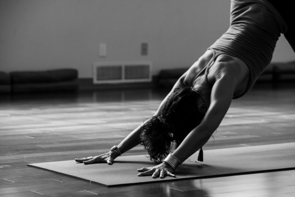 Vrouw doet rekoefening op yogamat in studio.