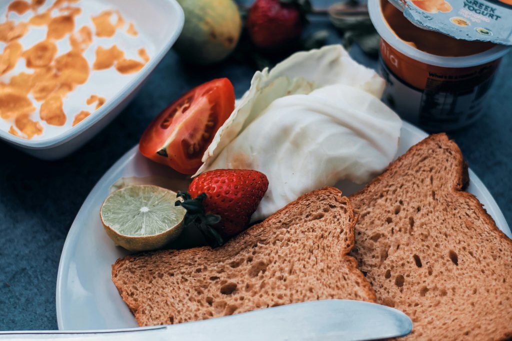 Een bord met brood, fruit en Griekse yoghurt.