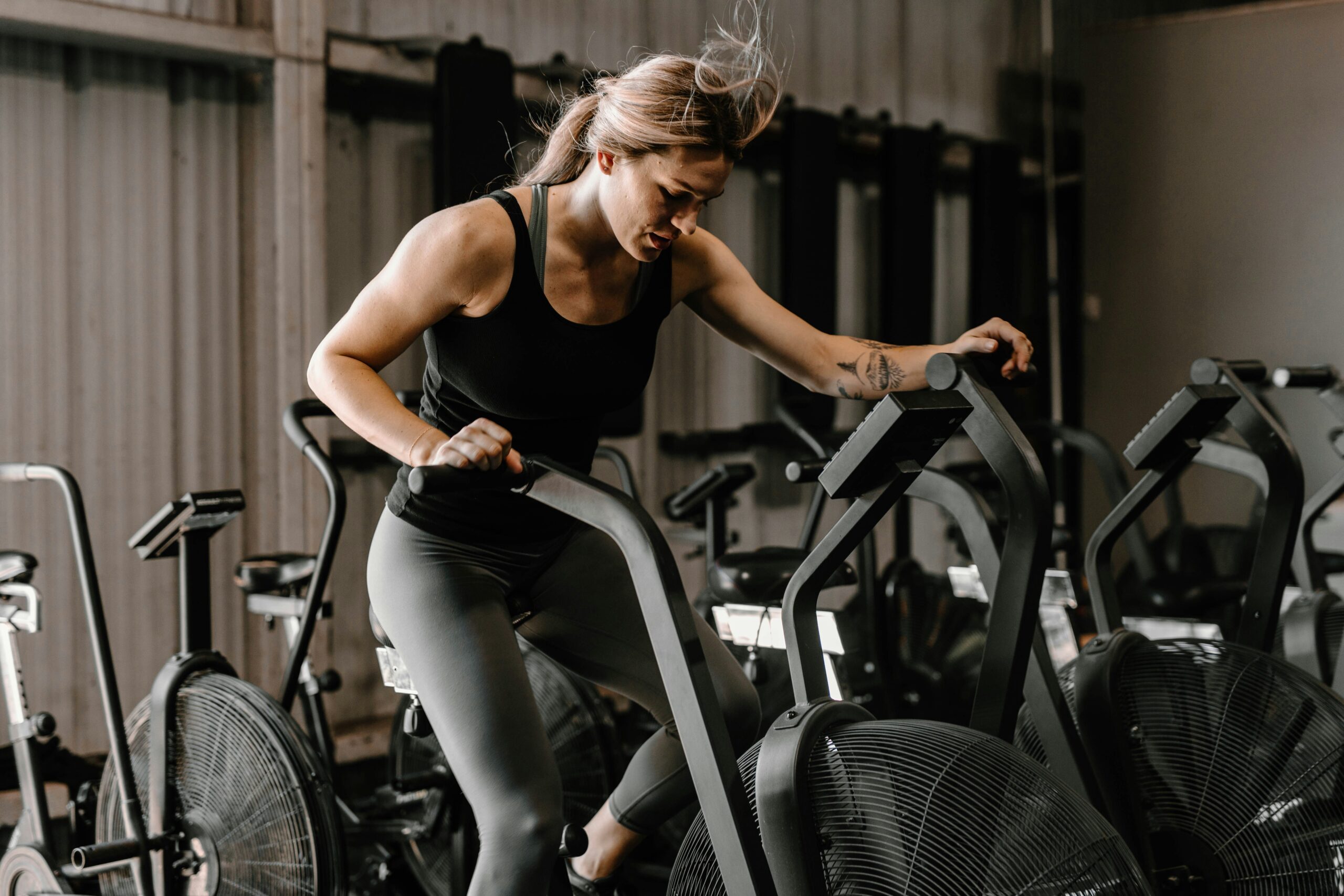 Technieken om krachtplateaus te doorbreken 1 Vrouw op trainingsfiets in de sportschool bezig met een workout.