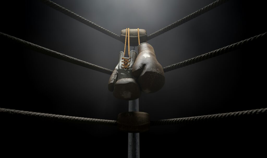 Zwarte bokshandschoenen hangen op een boksring touw.