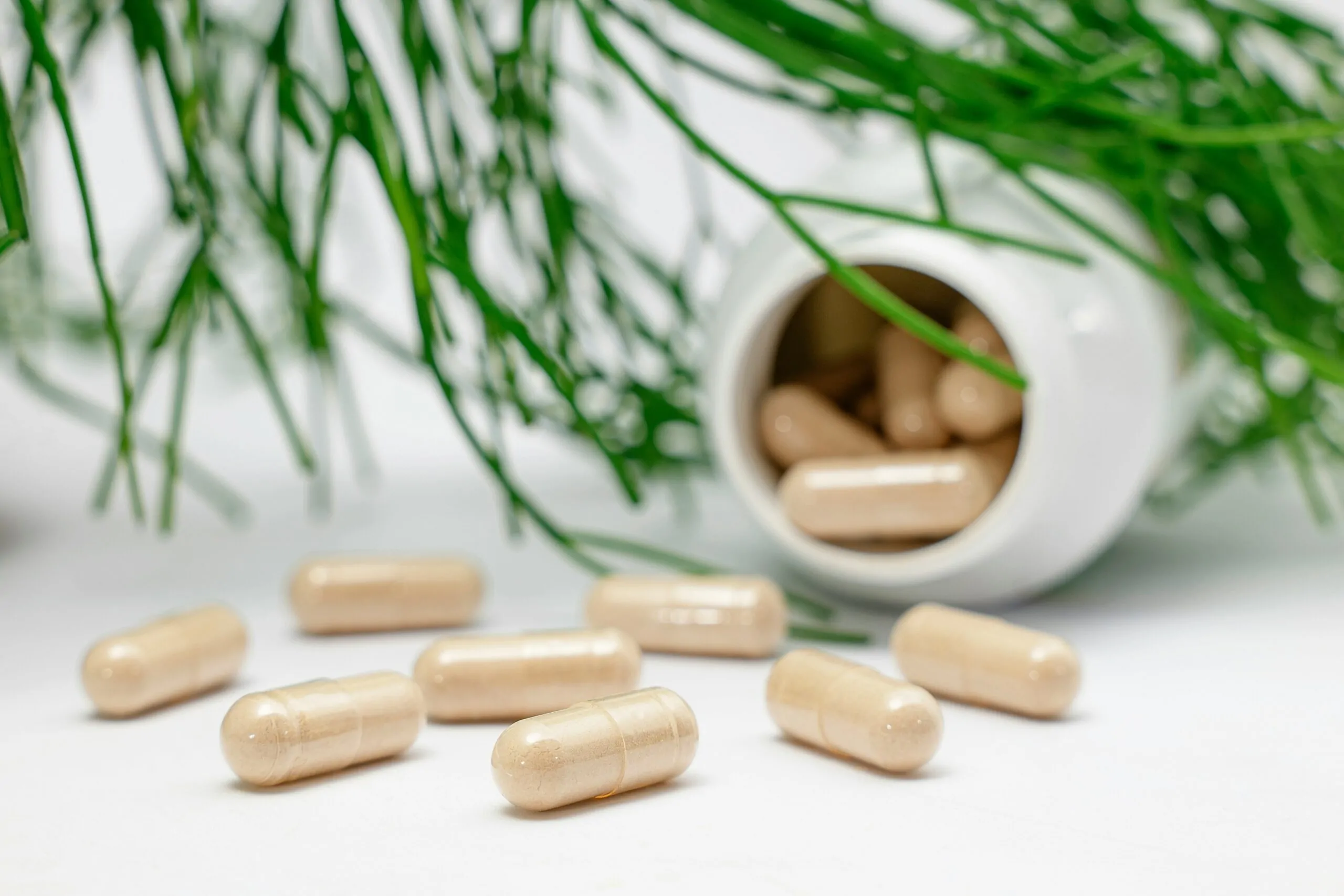 Top 5 supplementen die wel werken 3 Supplement capsules liggen verspreid naast een pot.